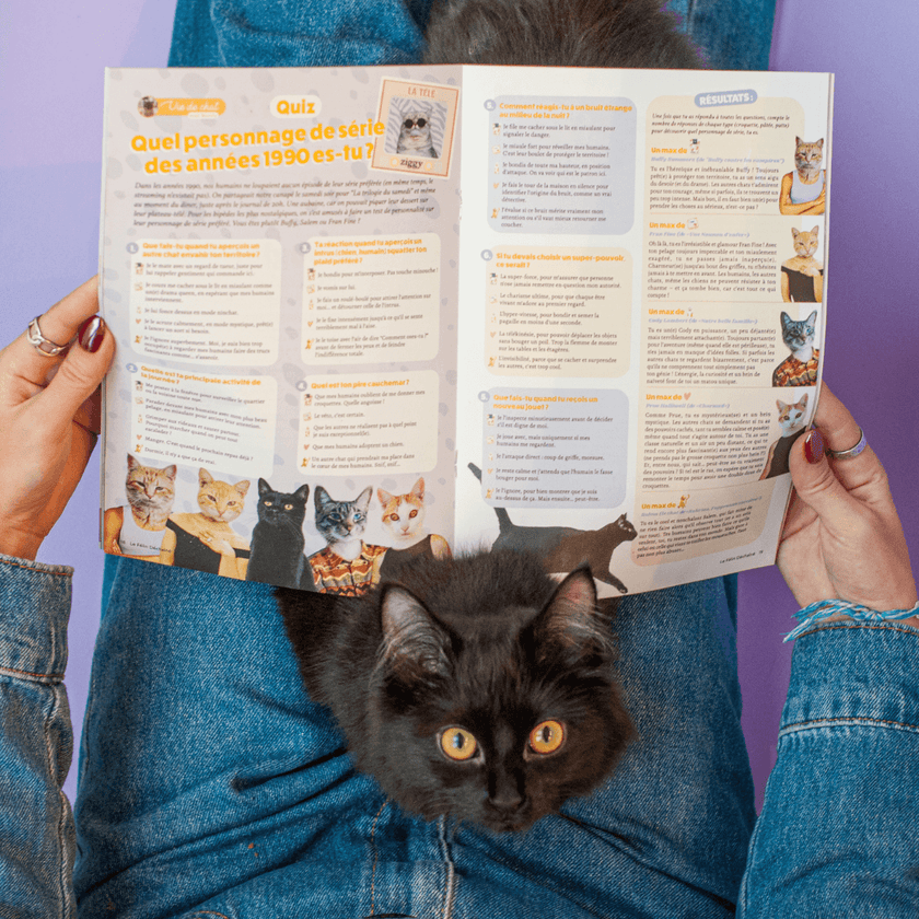 Chaton noir qui nous regarde en train de lire le Magazine le Félin Déchaîné de la marque pour chat Ziggy, édition n°8